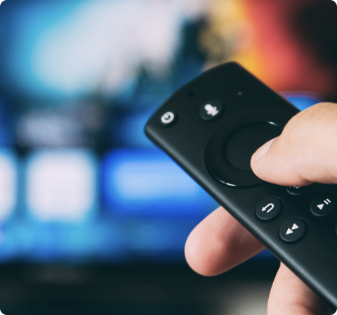 Photo of a hand holding a  TV remote control.