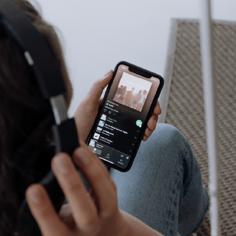 Person listening to programmatic audio ads via Spotify on their smartphone with over the ear headphones on